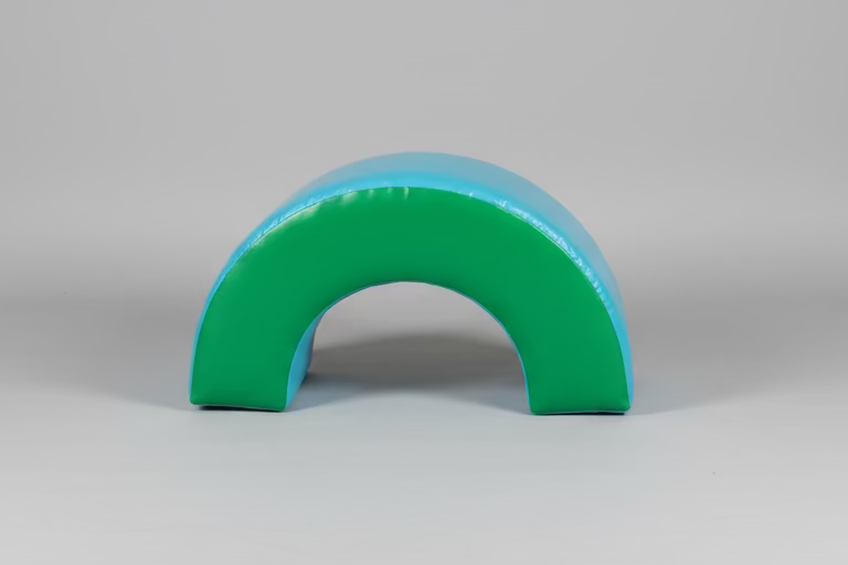 Curved blue and green foam roller on a tiled floor with black bean bags and a window in the background.